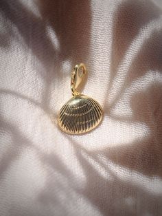 Add to your story with this gold sea shell charm. Choose from a regular jump loop or lobster clasp to make it your own.Planning on purchasing a chain for this and need help attaching it? Let us know and leave a note during checkout! This item will arrive separate/detached if no note is left.✦ DETAILS ✦✧ Gold Filled Sea Shell Pendant - 15mm x 17mm.✧ 14kt Gold Filled Loop or Clasp✧ Chains sold separately.✧ All Ke Aloha Jewelry pieces come packaged thoughtfully, beautifully, and ready for gift givi Gold Jewelry With Starfish Charm, Gold Metal Jewelry With Starfish Charm, Yellow Gold-plated Charms With Lobster Clasp, Gold Round Pendant Charm With Pearl, Elegant Gold Shell With Lobster Clasp, Gold Shell-shaped Jewelry With Starfish Charm, Gold Round Pendant Charm With Lobster Clasp, Brass Charms With Lobster Clasp For Gift, Gold Shell-shaped Charm Necklaces With Lobster Clasp