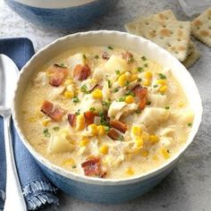 a bowl of corn chowee with crackers on the side and a blue napkin