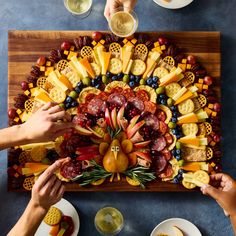 people are making a turkey shaped platter with cheeses, fruit and crackers