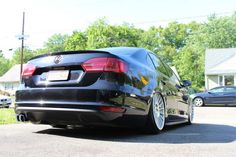 the rear end of a black car parked in front of a house