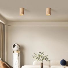 a living room filled with furniture and a white couch next to a tall vase on top of a wooden table