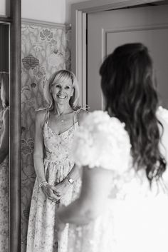 a woman standing in front of a mirror looking at herself in the mirror and smiling