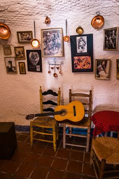 there is a guitar on the table and two chairs in front of it with pictures above them