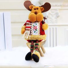 a stuffed animal wearing a sweater and holding a toy in its paws, sitting on a white surface