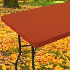 a red table sitting on top of a pile of leaves