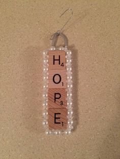 a wooden sign that says hope hanging from a wall with beads and string attached to it