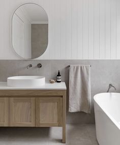 a bathroom with a sink, mirror and bathtub next to each other in front of a white wall