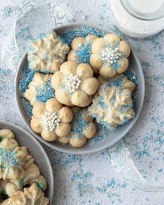 two bowls filled with cookies and blue sprinkles on top of a table