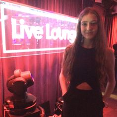 a woman standing in front of a live lounge sign