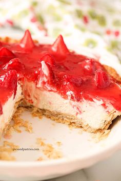 a cheesecake with strawberries on top is cut in half and sits on a plate