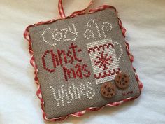 a cross stitch christmas ornament hanging on a bed