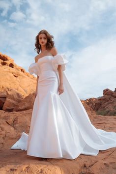 a woman in a white wedding dress standing on rocks