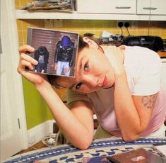 a woman is holding up an item in front of her face while looking at it