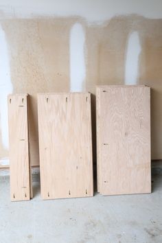 three plywood boards are lined up against the wall