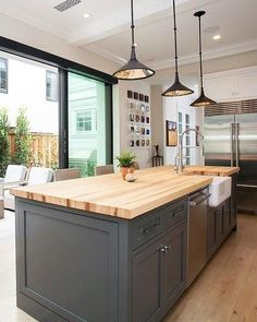 a large kitchen with an island in front of a sliding glass door that leads to the outside