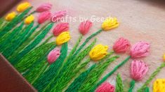 some pink and yellow tulips are on a piece of fabric with green grass