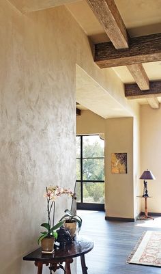 a living room filled with furniture next to a tall white wall and wooden flooring