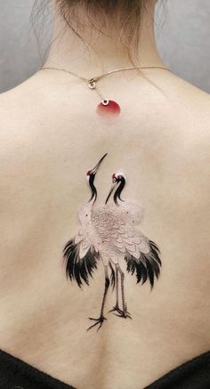 a woman's back tattoo with two birds on it