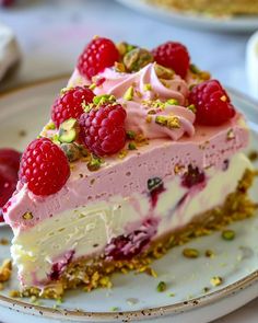 a piece of cake with raspberries and pistachios on it sitting on a plate