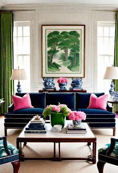 a living room with blue couches, pink and green pillows and paintings on the wall