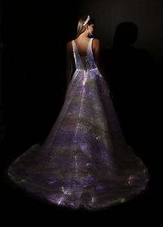 a woman in a purple and white dress is looking at the light from her back