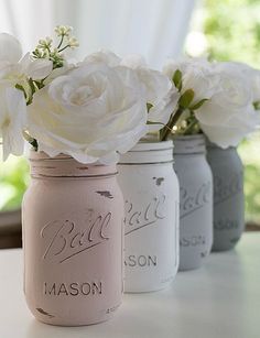 three painted mason jars with flowers in them