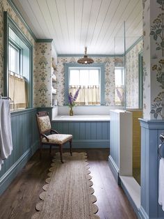 a large bathroom with blue walls and wood flooring, along with a white bathtub