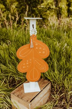 an orange paper cutout on top of a wooden box in the middle of some tall grass