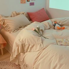 an unmade bed with several pillows and stuffed animals on the comforter in front of it