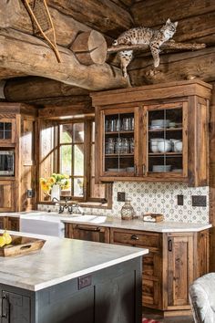 a kitchen with wooden cabinets and an island in front of the counter top, has a cat statue hanging from the ceiling