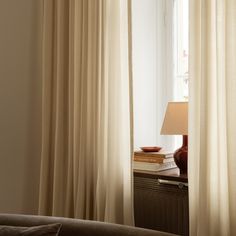 an open window with white curtains and a lamp