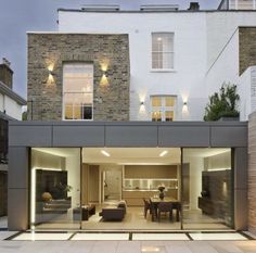 an open living room and dining area in front of a brick building with glass doors