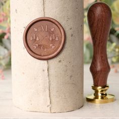 a wooden stamp sitting on top of a paper towel dispenser next to a flower pot