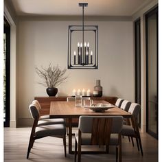 a dining room table and chairs with candles on the table in front of it,