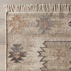 an old rug with fringes on the bottom and side, sitting on a wooden floor