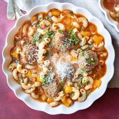 two bowls filled with pasta and meat in tomato sauce on top of a pink table cloth