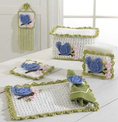 crocheted blue flowers and leaves are on the white tablecloths with green trim