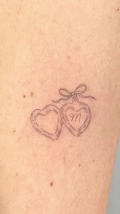 a tattoo with two hearts and a bow on it