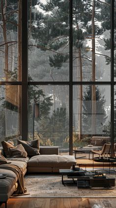 a living room filled with lots of furniture and large windows covered in raindrops