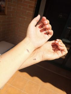 two hands holding each other with small tattoos on them