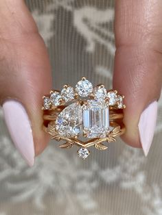 a woman's hand holding a gold ring with three stones and two leaves on it