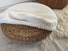 a basket sitting on top of a white rug next to a brown leather ottoman cover