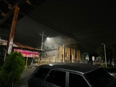 a black car parked in front of a building at night