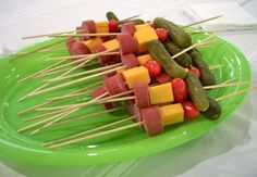 several skewers of meat and vegetables are on a green plate with toothpicks