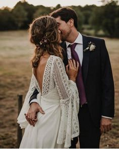 a bride and groom kissing in an open field