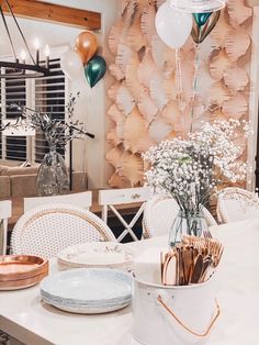 a white table topped with plates and vases filled with flowers