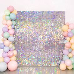 an arch made out of balloons and pastel colors on a table with a mirror backdrop