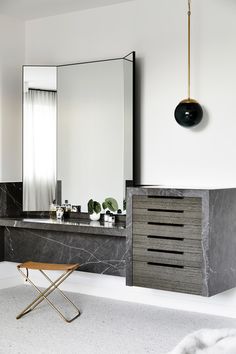 a modern bathroom with marble counter tops and black accents, along with a gold stool