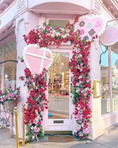 a pink store front decorated with flowers and hearts