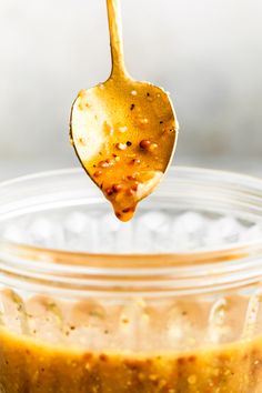 a spoon with some food in it on top of a glass jar filled with liquid